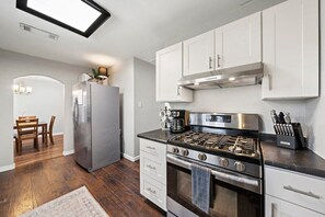 A sleek kitchen featuring stainless steel appliances lit by natural skylight ☀️