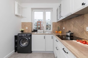Modern kitchen with white cabinets, a wooden countertop, and integrated appliances, including a black washing machine for convenience.