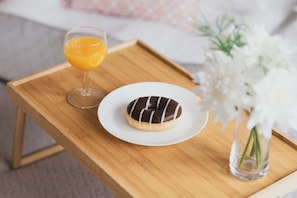 Wooden tray with a glass of orange juice, a dessert plate, and a white flower vase, adding a touch of elegance to the dining experience.