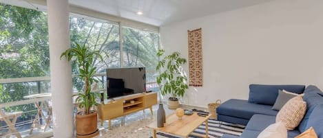 Sala de estar con smart TV, apps como Netflix, Youtube, Prime Video, etc. A un lado del balcón con un pequeño desayunador.