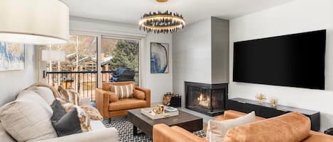 Comfortable living room with wood burning fireplace, sleeper sofa and sliding door to private balcony with view of Red Mountain