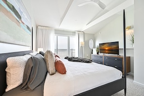 "Spacious modern bedroom with a full bath, balcony, and beach views."