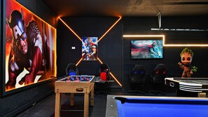 Superhero-inspired game zone with foosball, arcade seating, and bold wall art.