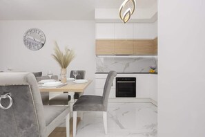 A contemporary dining area with a sleek table and velvet gray chairs, seamlessly integrated with the modern kitchen.

