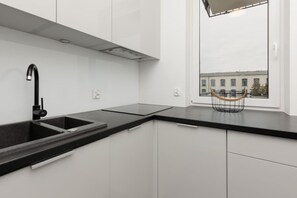 A sleek kitchen with white cabinets, black countertops, and minimalist design, featuring integrated appliances for a clean look.