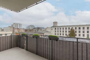 A balcony with grey railings overlooking an urban landscape, providing a comfortable outdoor seating area with a city view.