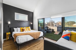 Upstairs bedroom #3 with a King bed, twin + trundle bed, and large sunny patio space with outdoor furniture & cornhole.