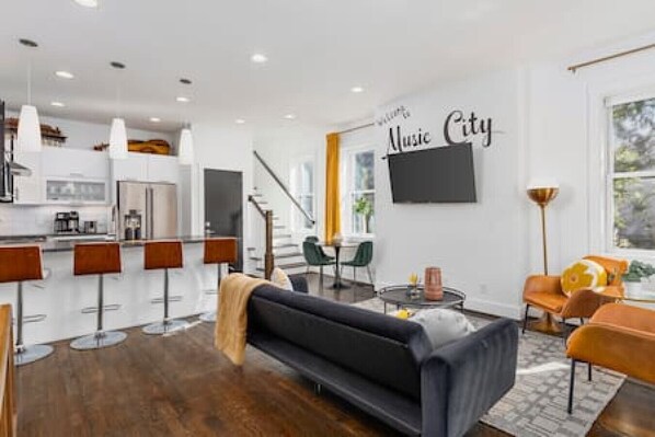 Living room with a Smart TV, comfortable couch and large front porch just outside the entryway.