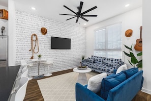 Living room with two comfy couches, a ceiling fan, and a Smart TV with all the streaming apps. Lots of natural light in this home with unique decor highlighting Nashville's roots in music.
