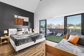 Upstairs bedroom #3 with a King bed, twin + trundle bed, and large sunny patio space with outdoor furniture & cornhole.