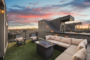 Spacious rooftop deck with a gas grill, fireplace, plenty of seating, and views of the city.