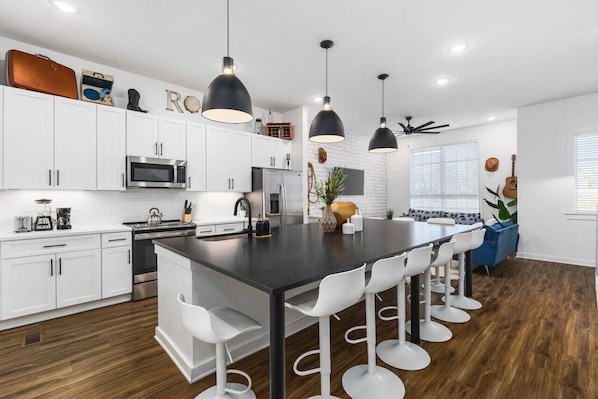 Huge kitchen on the main floor of the house with a massive island, seating for 10, and all the appliances / supplies you'd need to cook a meal.
