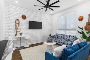 Living room with two comfy couches, a ceiling fan, and a Smart TV with all the streaming apps. Lots of natural light in this home with unique decor highlighting Nashville's roots in music.