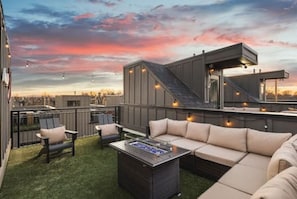 Spacious rooftop deck with a gas grill, fireplace, plenty of seating, and views of the city.