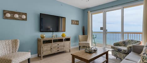 Living Room - Relax in luxury and comfort in this gorgeous living space featuring a large flat-screen TV, coastal decor, and a private balcony with breathtaking beach views.
