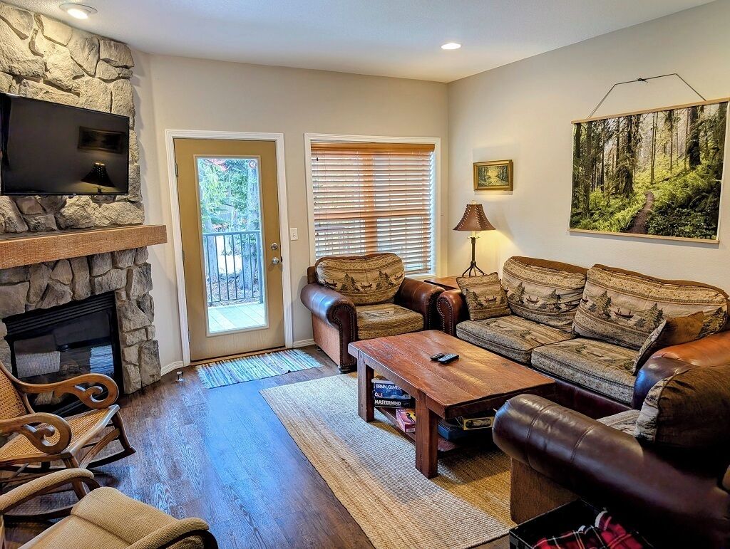 Cozy living room with a flat screen TV, gas fireplace, and entrance to private balcony
