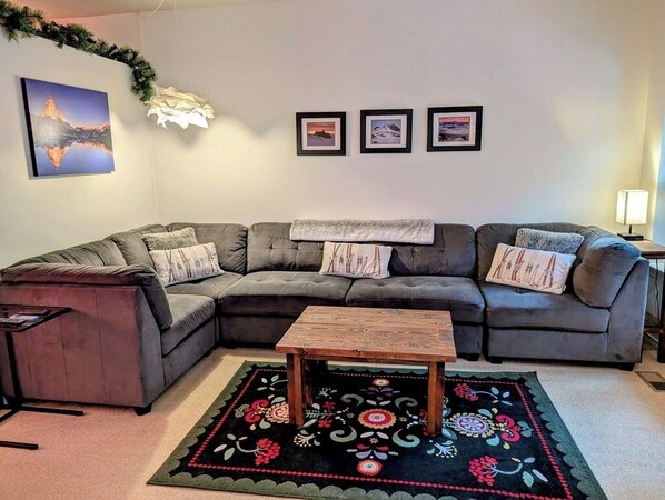 Large comfortable couch in the living room, windows overlook the creek