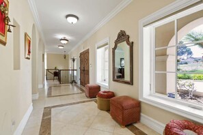 From this view, the home's stunning architecture is on full display. The hallway leads to a sleek, modern staircase descending gracefully to the lower level, inviting exploration of spacious living areas bathed in natural light from above.
