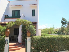 Villa Cosima mit überdachter Terrasse und Begrünung vor dem Haus und Parkplatz