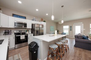 Fully equipped kitchen with stainless steel appliances and breakfast bar that seats four