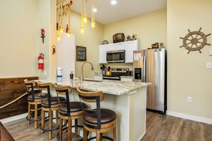 Beautiful kitchen area with granite counter tops, bar stools and unique lighting