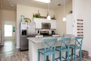 Fully equipped kitchen with stainless steel appliances and breakfast bar with seating for three