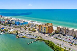 Aerial view of condo building. Beach in front. Sitting/fishing pier in back. 
