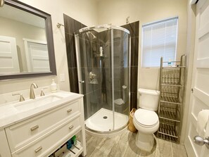 Shower stall, sink & toilet with towels and toilet paper.