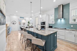 This stylish kitchen boasts a spacious island, top-of-the-line appliances, and a sleek backsplash for an elevated cooking experience.