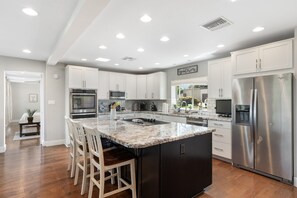 Kitchen with bar seating, granite counter tops, hardwood floors, and state-of-the art appliances.