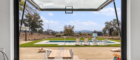 view of back patio and pool area from kitchen hydraulic pass-thru window