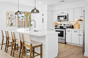 Fully-stocked kitchen with stainless steel appliances and island with barstool seating for four