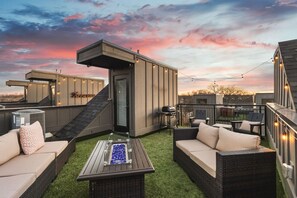 Spacious rooftop deck with a gas grill, fireplace, plenty of seating, and views of the city.