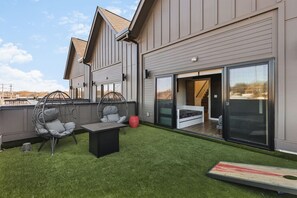 Large patio with cornhole and outdoor furniture, attached to bedroom #3.