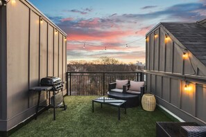 Spacious rooftop deck with a gas grill, fireplace, plenty of seating, and views of the city.