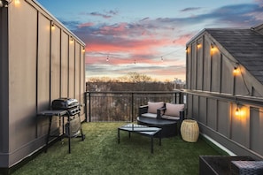 Spacious rooftop deck with a gas grill, fireplace, plenty of seating, and views of the city.