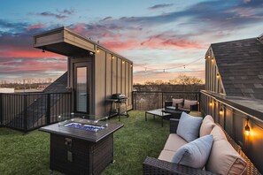 Spacious rooftop deck with a gas grill, fireplace, plenty of seating, and views of the city.