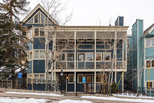 Elegant Victorian facade with decorative trim, dual level porches, and snowy curb appeal.