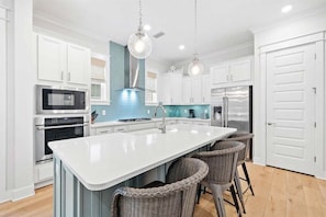 A sleek and stylish kitchen with bar seating, stainless steel appliances, and a fresh coastal vibe.