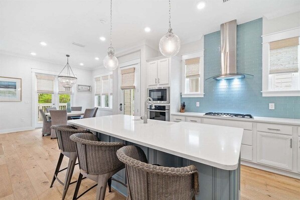 A fully equipped kitchen with high-end appliances, a large island, and stylish pendant lighting.