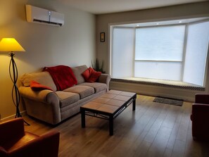 Living room with full size couch, two side chairs, A/C & Heating Ductless unit