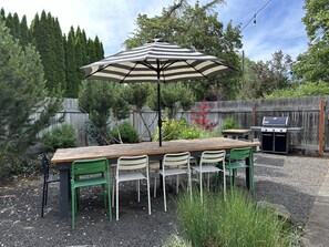 Outdoor dining table for 12 in fenced back yard, with Weber propane BBQ.