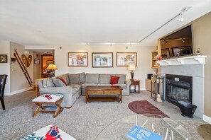 A spacious and cozy living area with a large sectional sofa, ski-themed decor, and warm wood accents.
