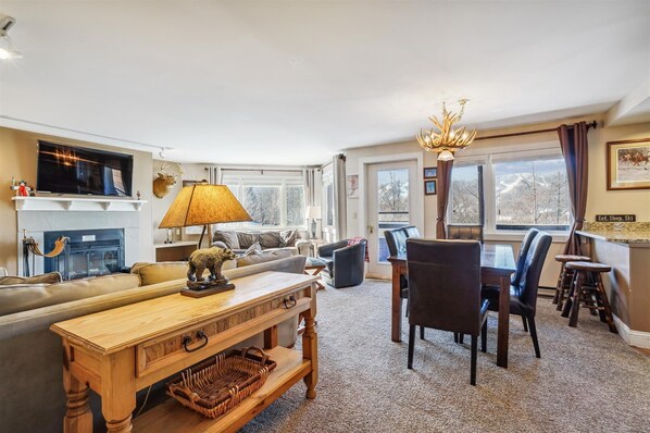 A cozy, rustic living and dining space with a fireplace and mountain views.