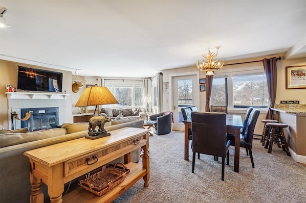 A cozy, rustic living and dining space with a fireplace and mountain views.