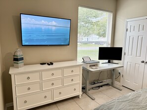 This bedroom has a queen size bed, TV, desk, and dresser