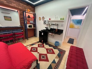 sala de estar com soft kitchen e bancada de vidro para refeições