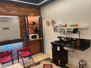 sala de estar com soft kitchen e bancada de vidro para refeições