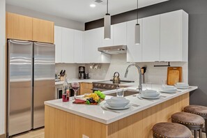 Fully equipped modern kitchen stocked with all culinary essentials and featuring brand new stainless steel appliances with bar seating.