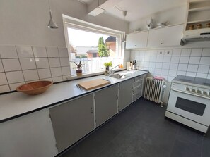 Kitchen is spacious and bright. It features a long countertop, stove and oven.